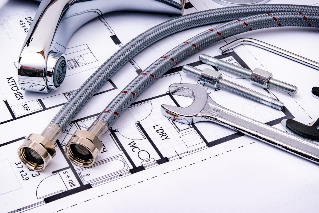 about-01 Close-up of plumbing tools and faucet on top of an architectural blueprint, perfect for hardware and construction themes.